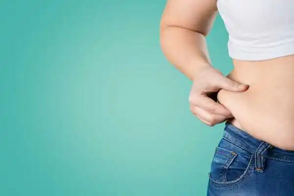 Image of woman pinching her love handles to show weight gain Binton